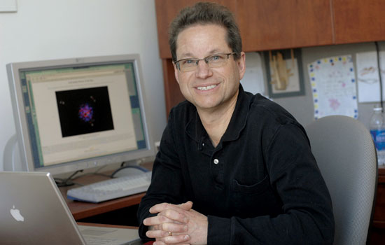 Professor sitting in office next to computers