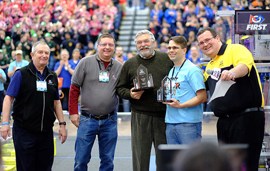 Five people posing for a picture at robotics competition.