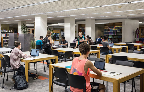students sitting at tables in the library.