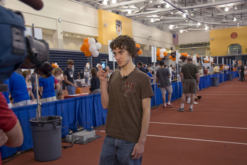 Student holding phone posing for camera at an event