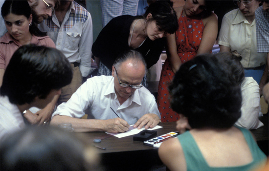 Person signing document at crowded table