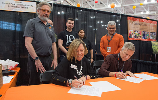 People signing documents at conference