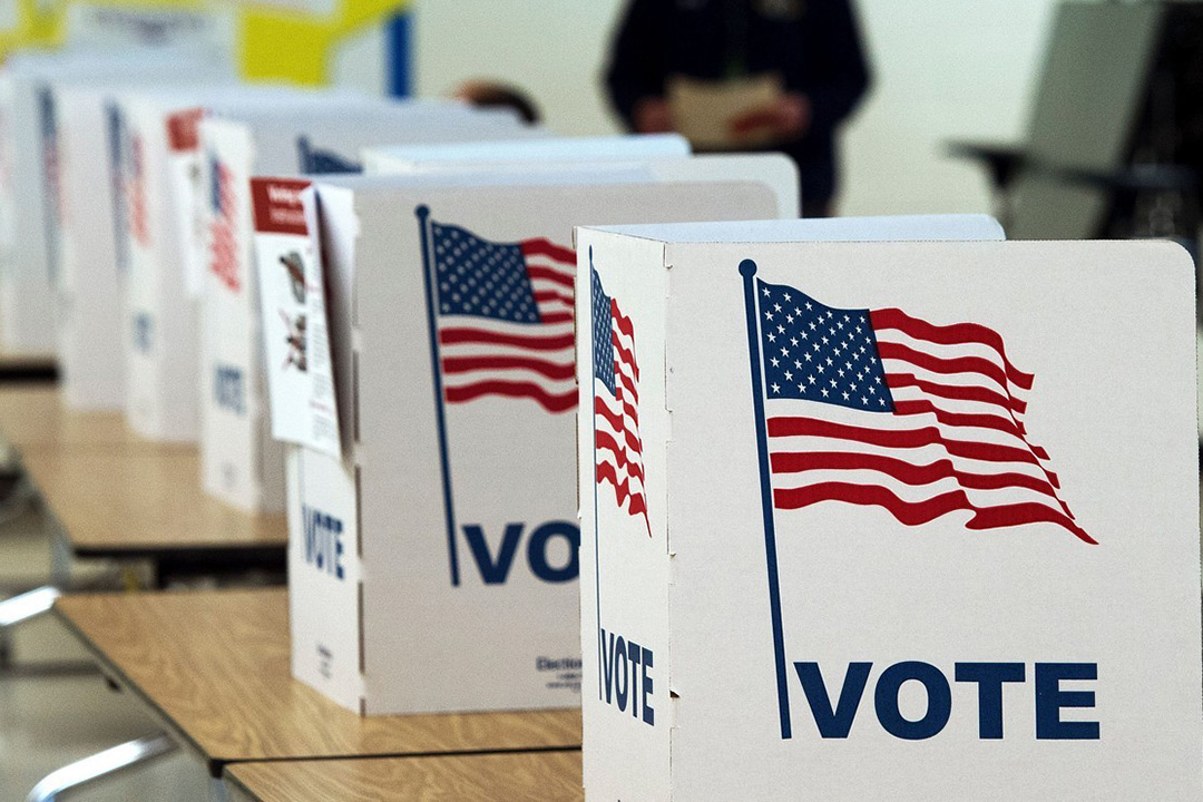 Voting booth stations set up at different tables, no one is sitting at them.