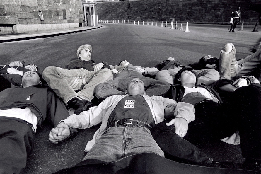 A photo taken from the exhibition which features a group of men and women laying down in the street with their arms and legs locked together in protest.