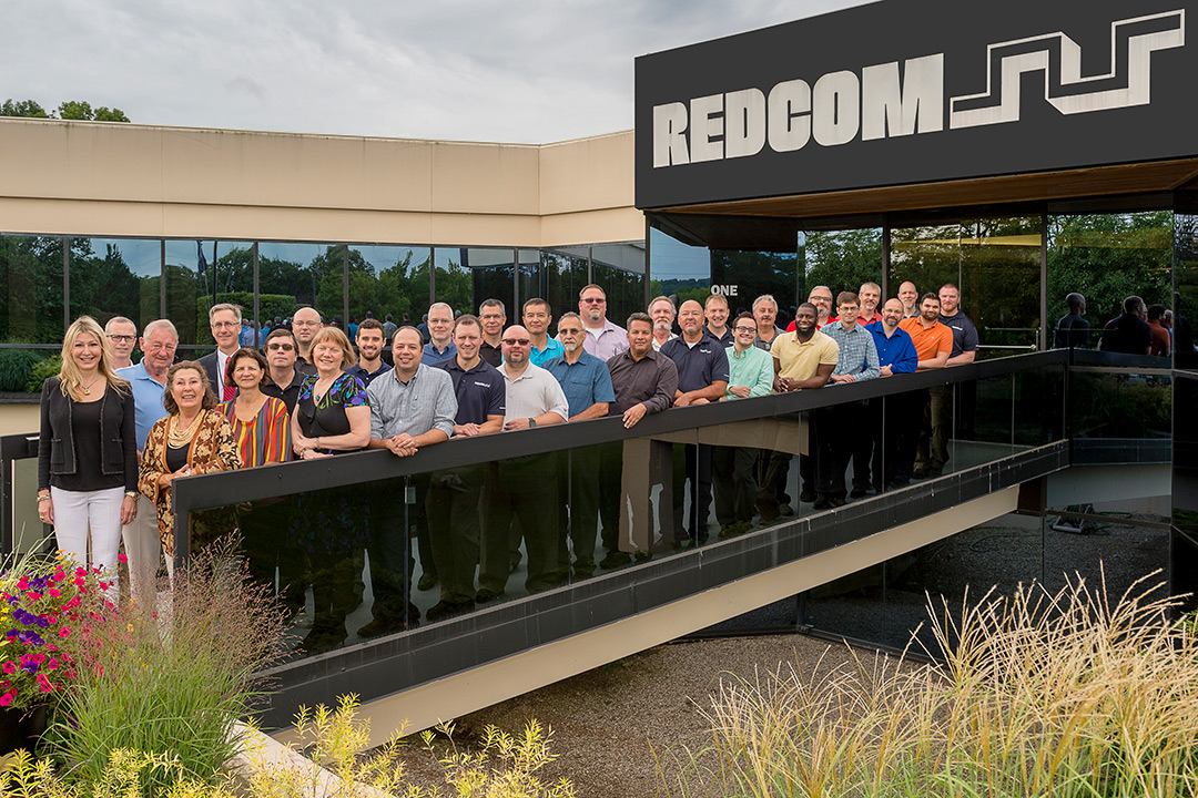 A group of people gathered on a short foot-bridge leading into REDCOM Laboratories.