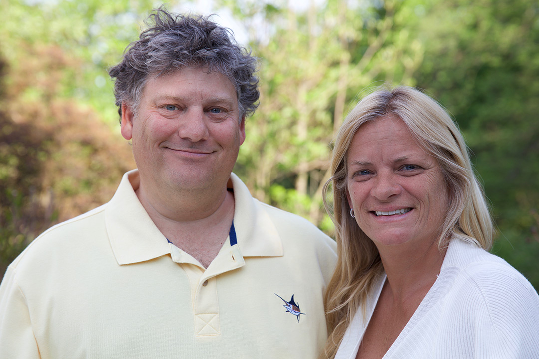 David and Patricia pose together outdoors and smile at the camera.