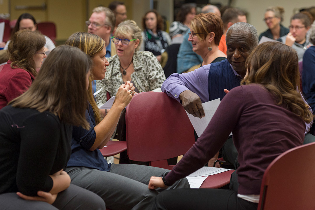 A group of people, mostly women, sit and talk in groups.