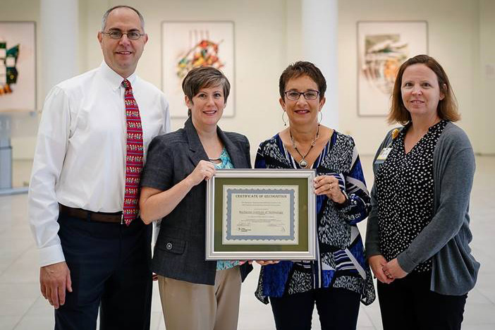Four contributors from RIT and University of Rochester pose with their award certificate.