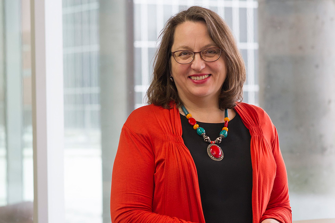 A nice portrait of Doreen Edwards wearing a red cardigan, black shirt and colorful statement necklace.