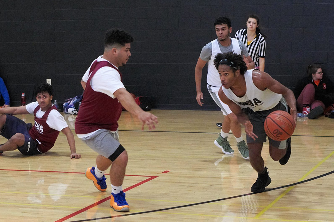 TJ Bartholomew runs and dribbles a basketball as another player tries to block him.