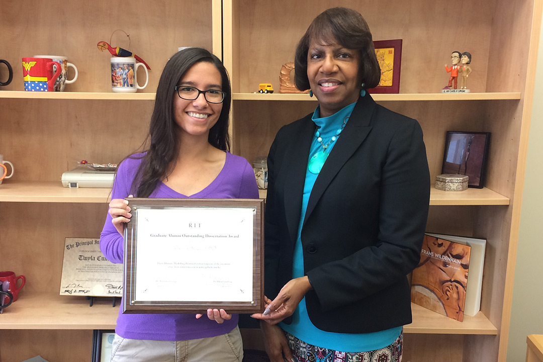 Triana Almeyda holds her Ph.D. Dissertation Award and poses for a photo next to Twyla Cummings.