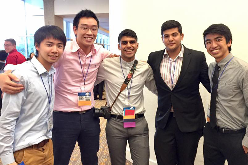 Group of five male students standing in semicircle with arms around each other