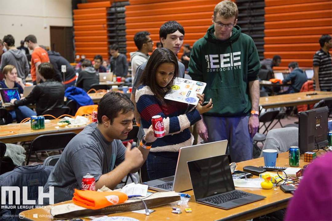 Groups of students looks at laptops along several long tables