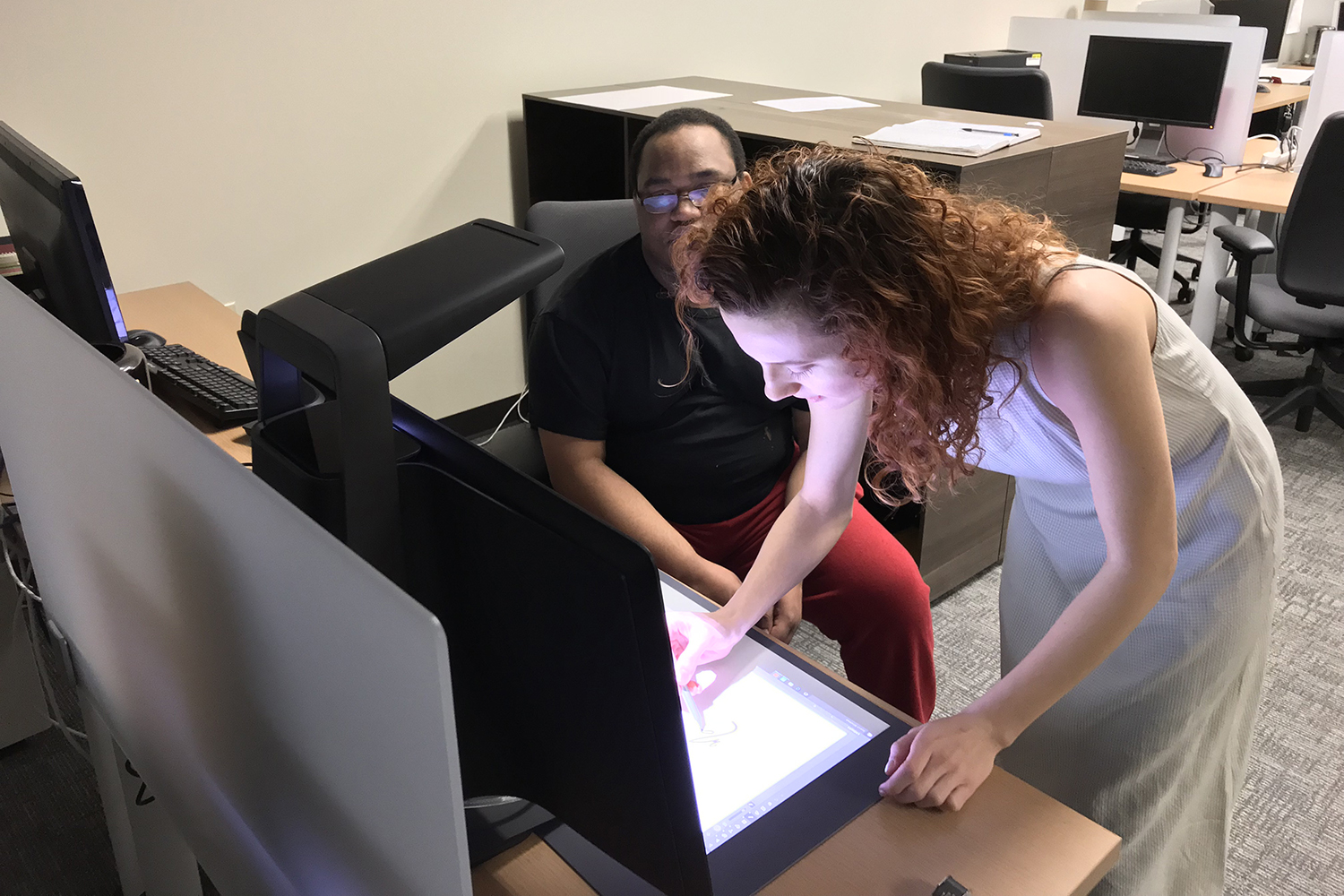 A student draws on a light table as another watches.