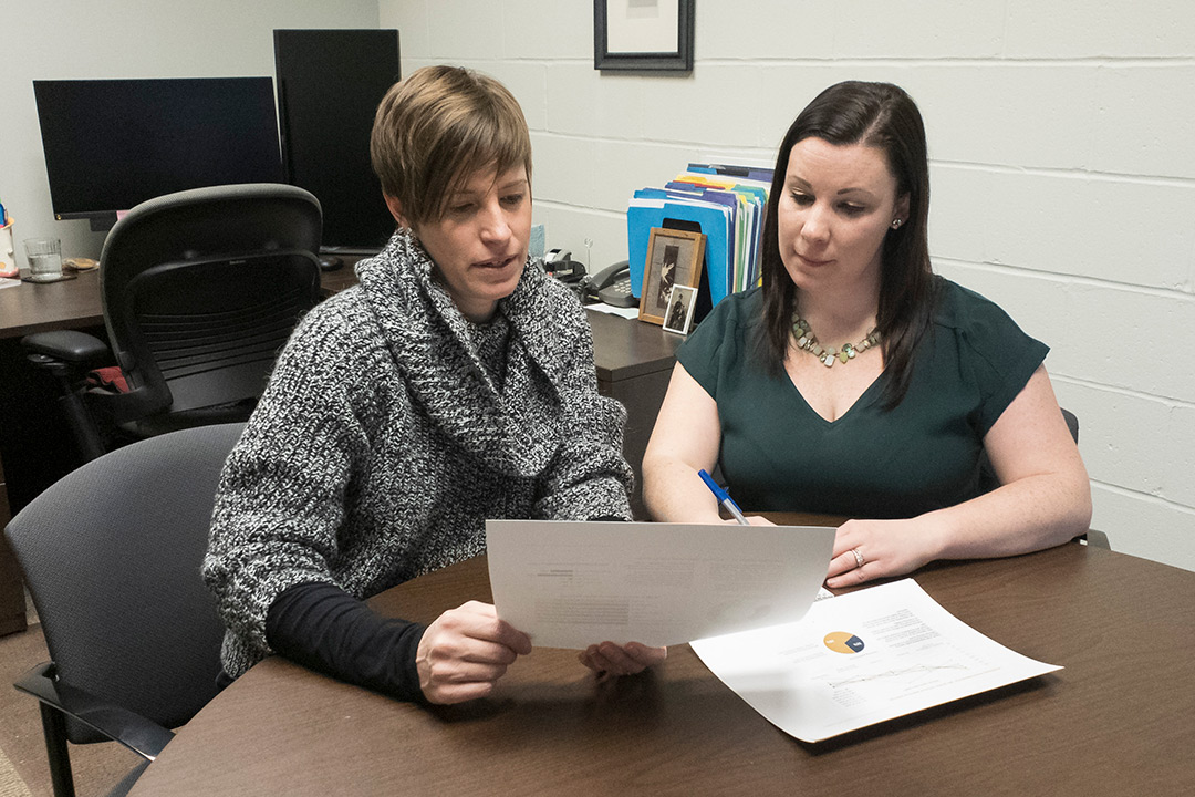 Two women sitting at table looking a sheet of paper