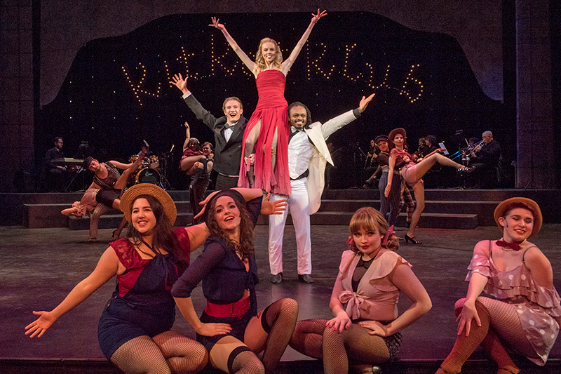 actors dressed in 1930s cabaret attire pose on stage