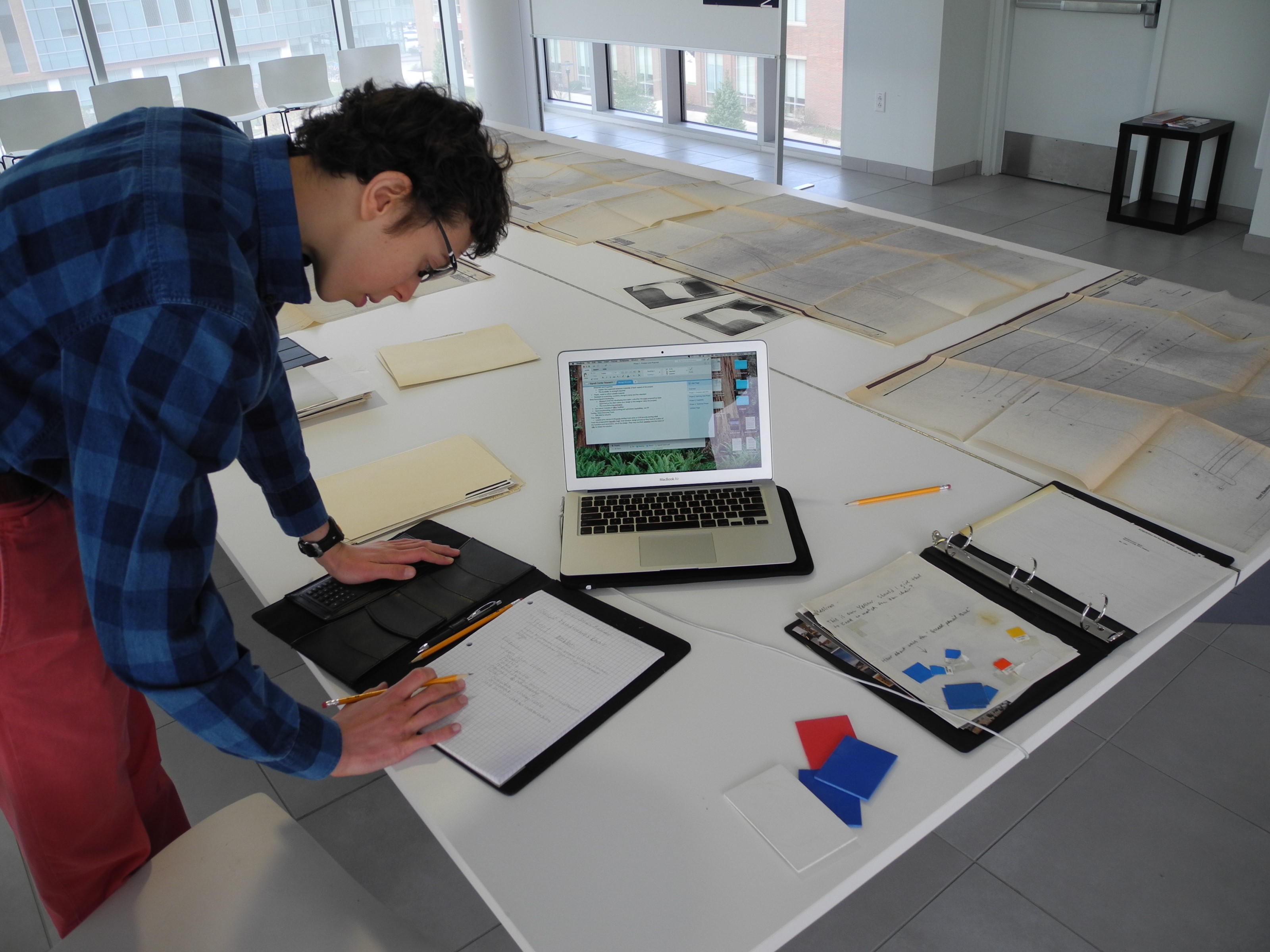 Anglemyer leaning over a desk in the Vignelli Center doing work