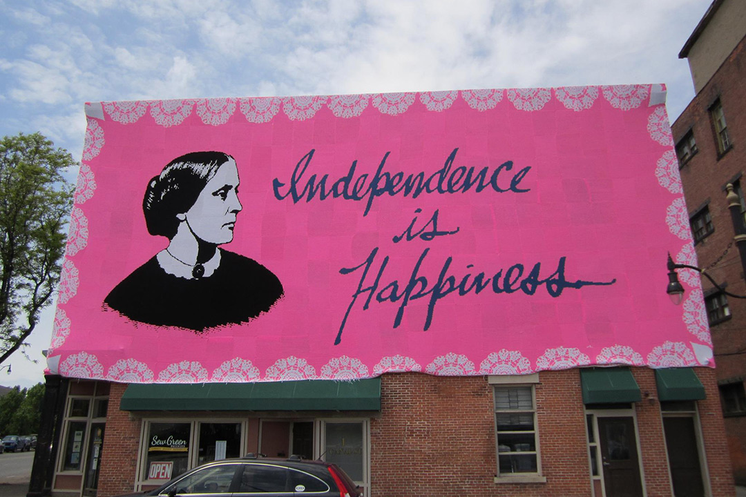 Pink banner with image of Susan B. Anthony that reads: Independence is Happiness