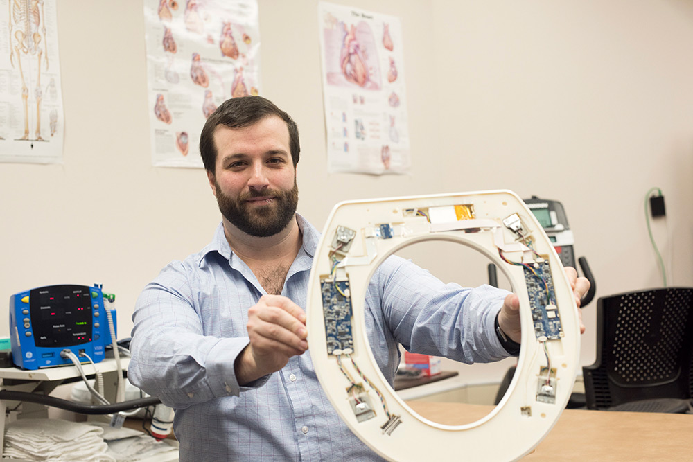 Researcher holds toilet seat with sensors attached to it.