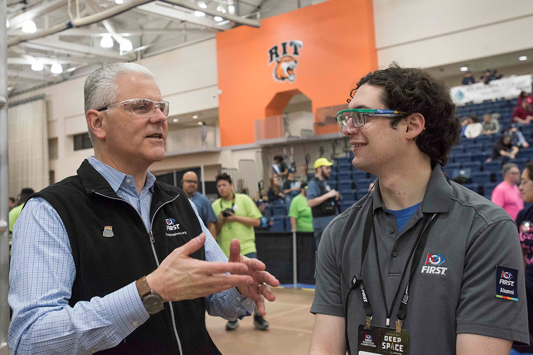 Two man with eye protection goggles stand and talk to each other