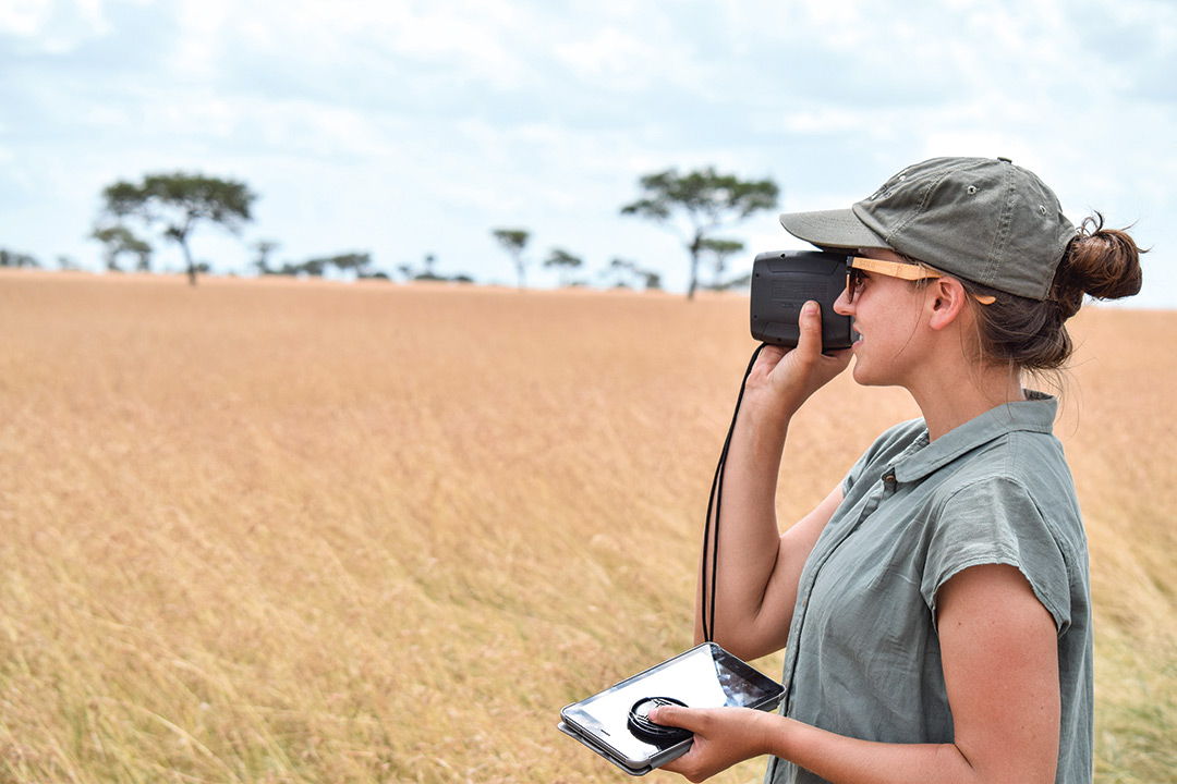 Woman looks though camera in the middle of a plain