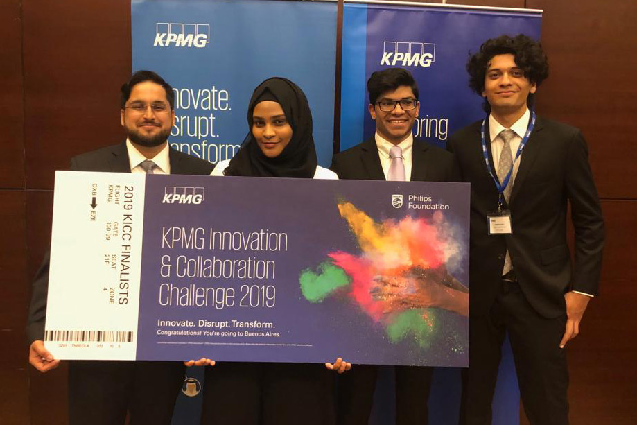 Four RIT Dubai students stand holding giant check