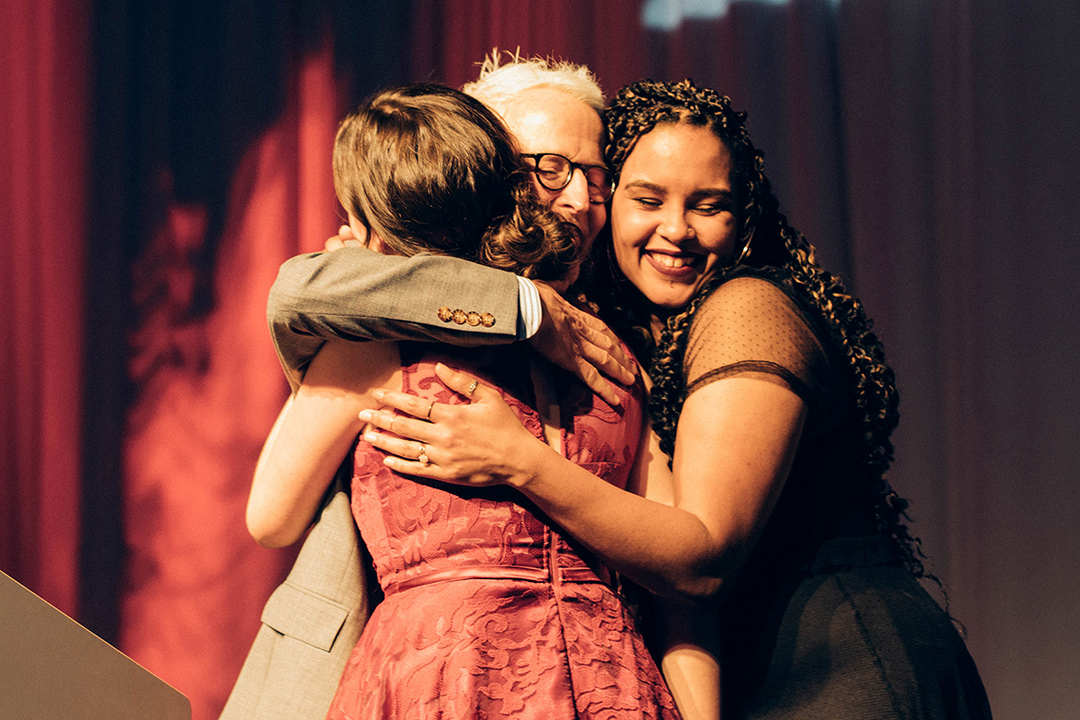 Chris Lyons and two of his former students share a hug