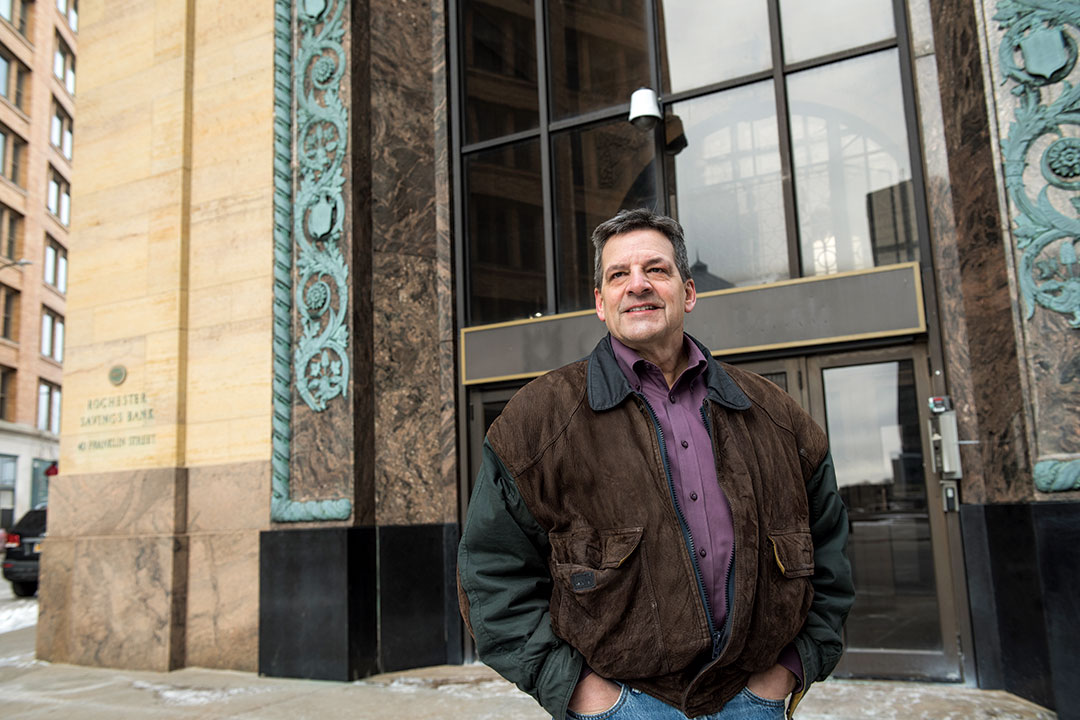 Man stands in front of downtown building.