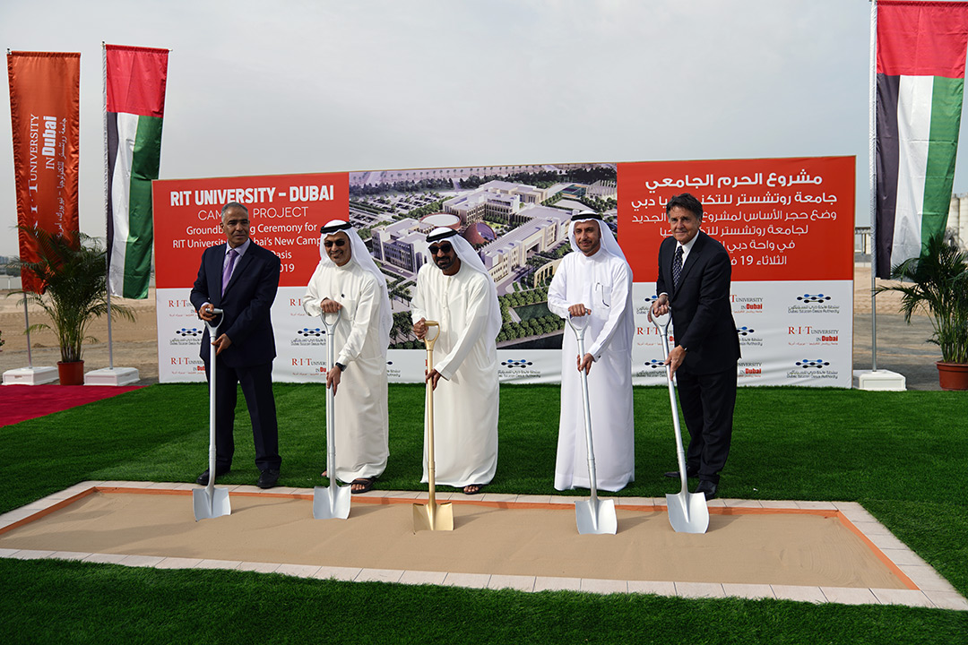 Five officials stick ceremonial shovels into a length of sand in Dubai