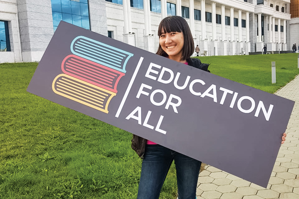 Woman holds sign that reads: Education For All.