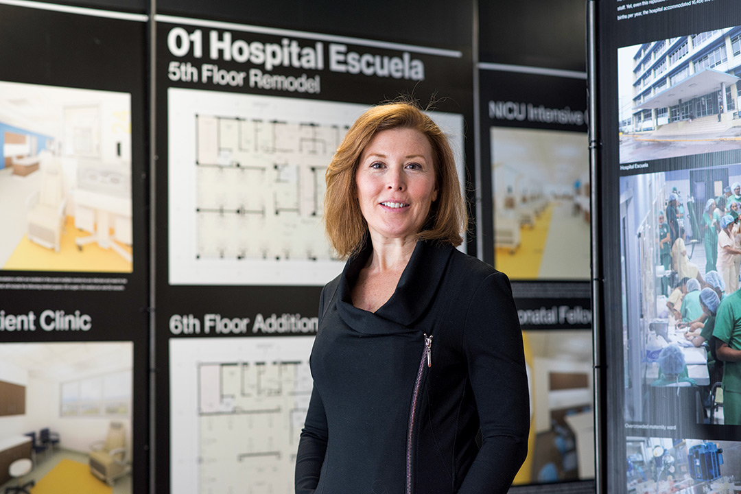 Woman stands in front of display of hospital floor plans