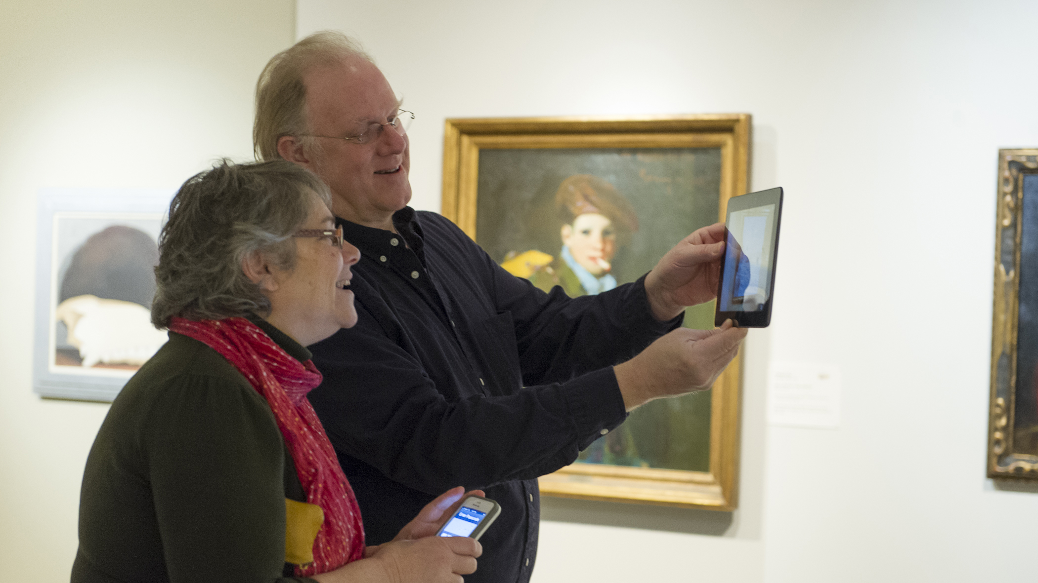 Two people looking at artwork on a tablet, in an art gallery.