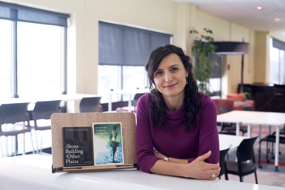 Woman sits at table with two books propped up on easel