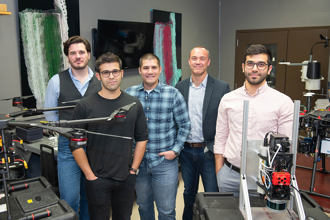 Professor and students stand with drone.