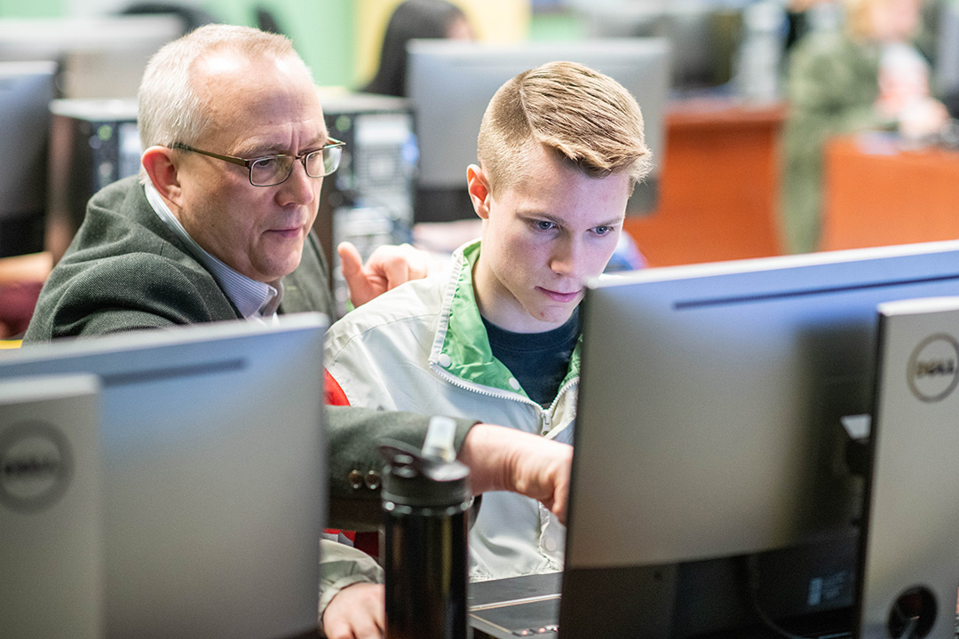 Professor and student work on a computer.