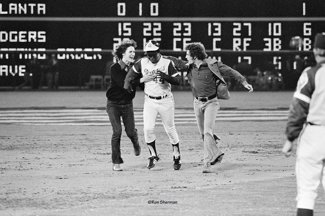 Hank Aaron rounds second base as two fans run beside him in 1974.