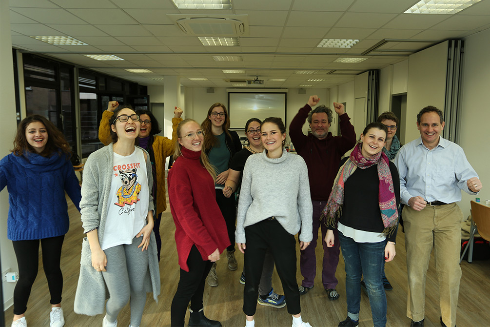 Group of men and women standing in classroom.