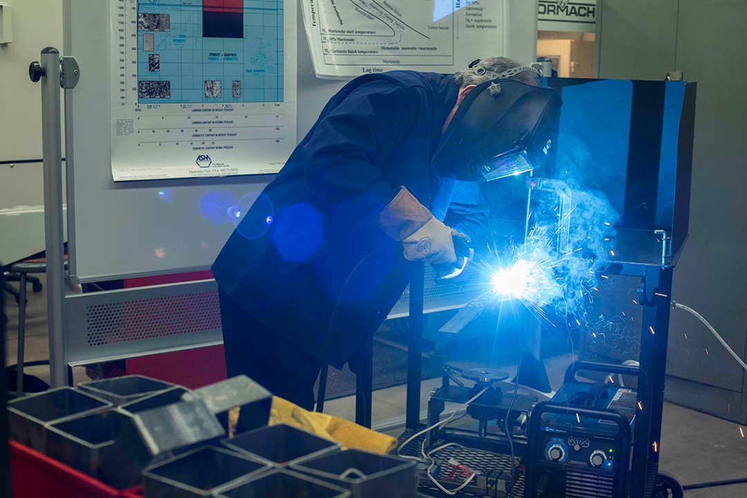 Worker cuts small metal beam with plasma arc cutting machine. 