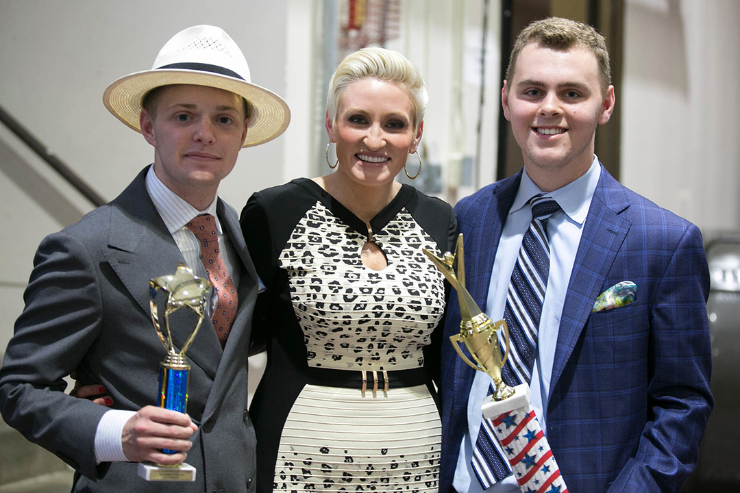 Students and woman stand holding trophies.