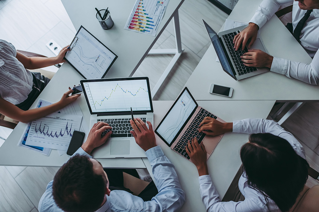 Overhead view of four people working on  laptops.