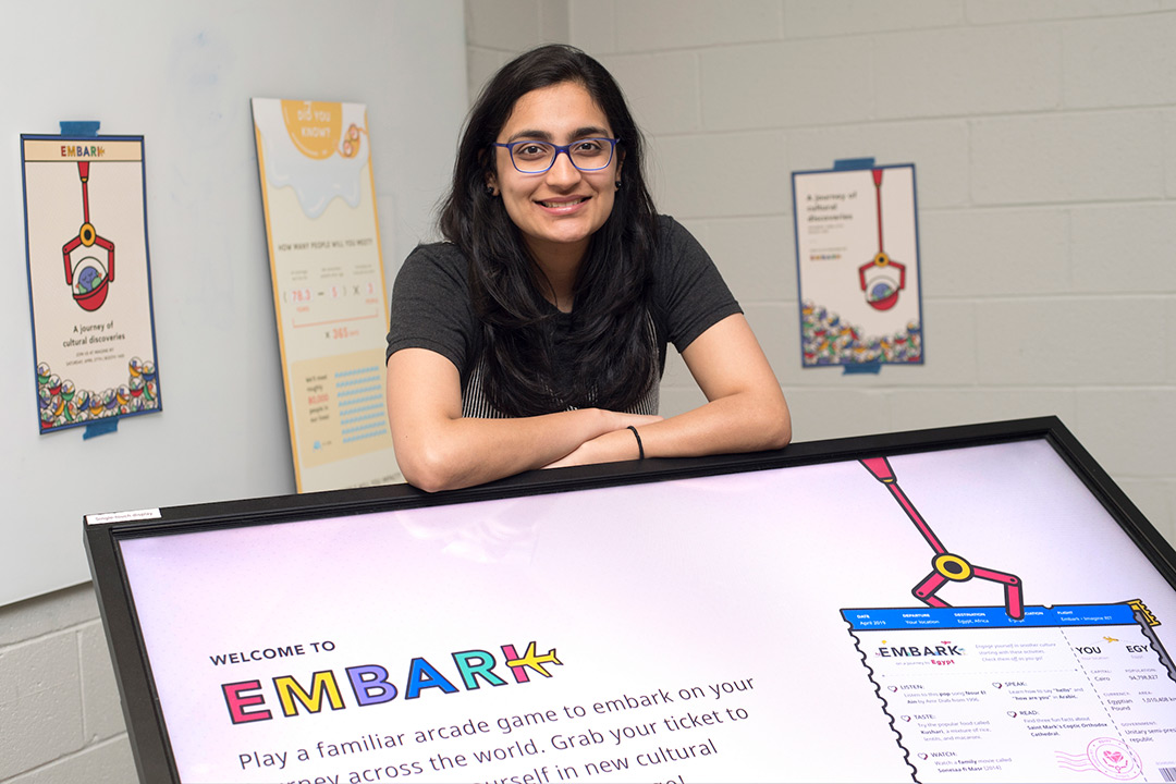 Woman poses ner display that reads: Welcome to Embark.