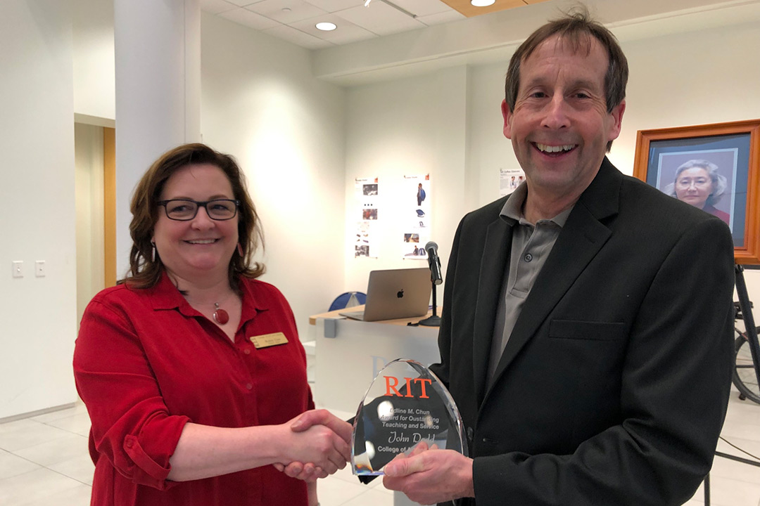 Man and woman pose with glass award.