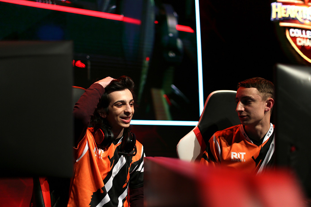 Two students sit in gaming chairs.