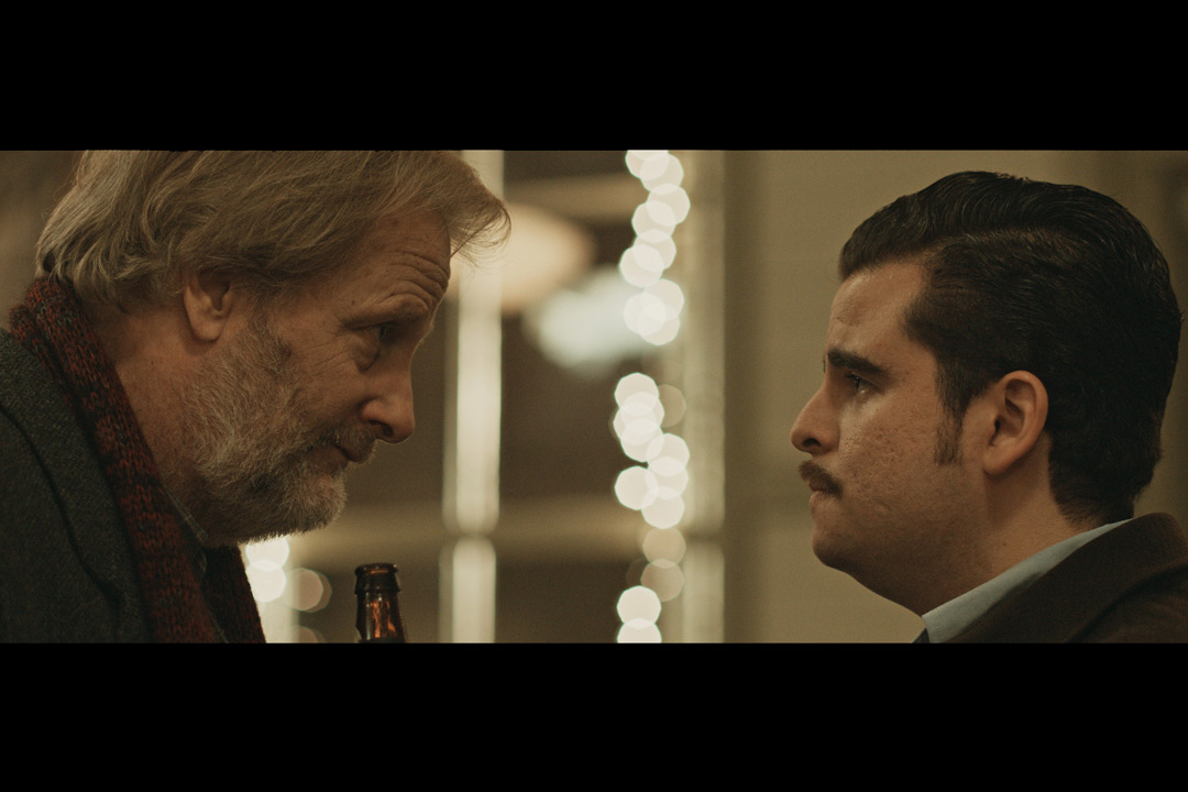 Screenshot from movie in which two actors look face-to-face.