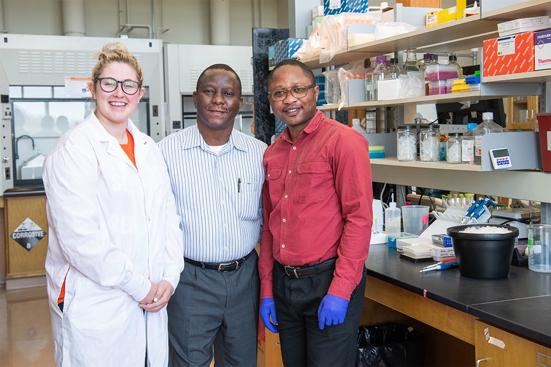 Three people smiling and standing in a lab