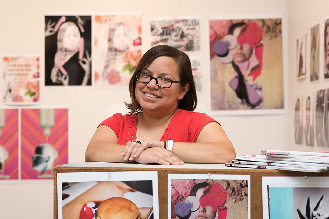 Student poses with images of artwork.