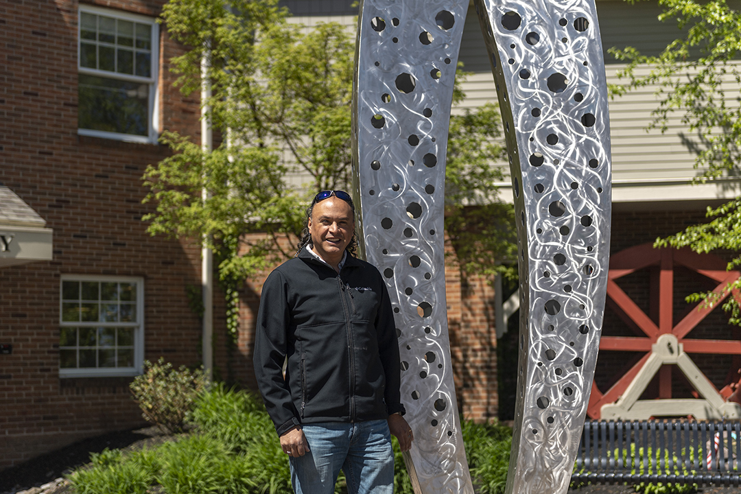 Carlos Caballero-Perez stands beside his newest sculpture, "Connection"