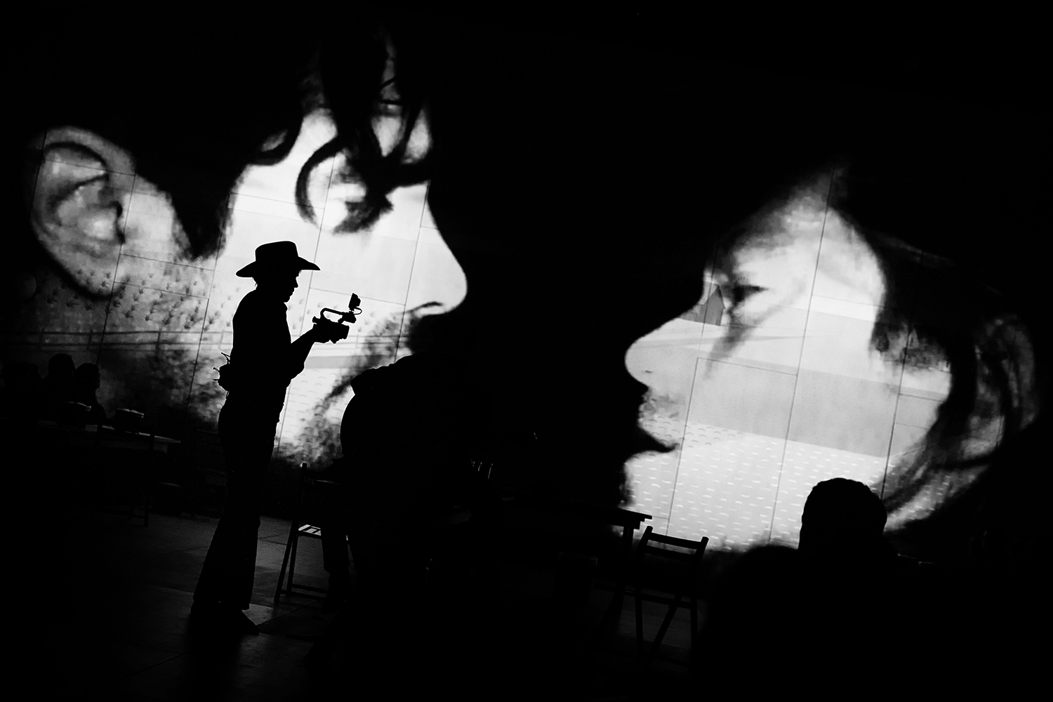 Actors stand in the dark in front of a video projection