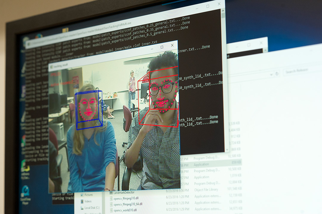 Computer monitor displaying two students with their faces outlined in red dots.