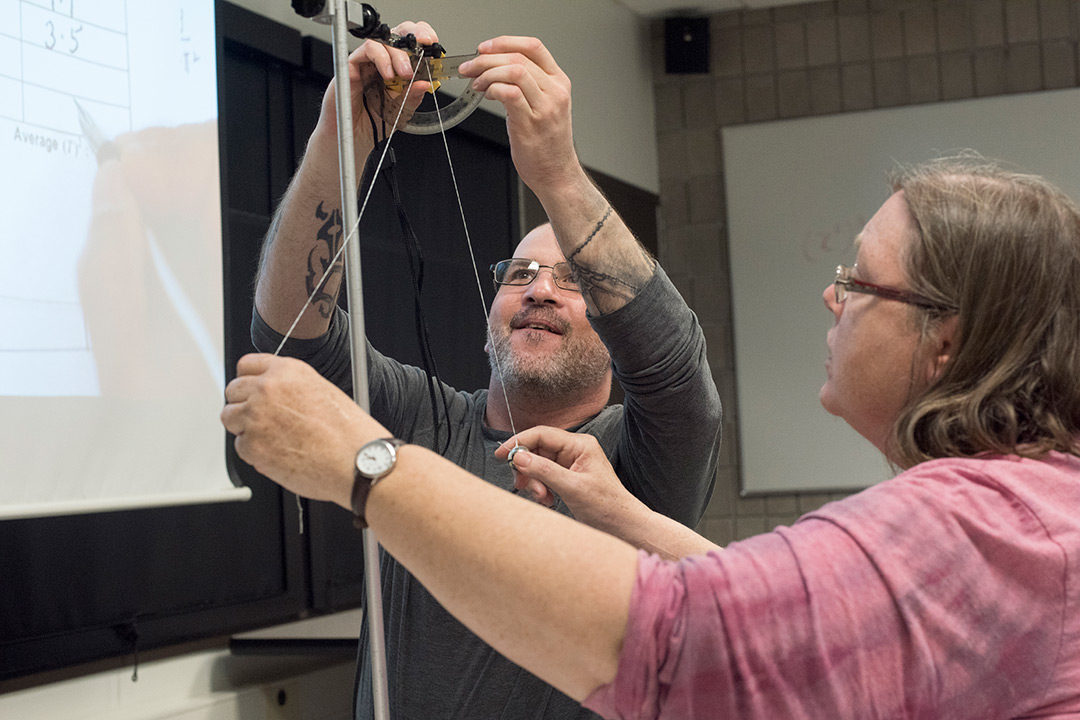 Adult students conduct experiment with protractor.